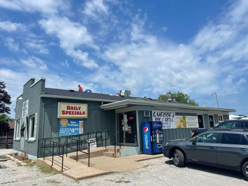 A small, one-story restaurant with a sign for daily specials, featuring a ramp and a Pepsi vending machine outside.