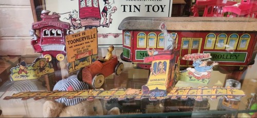 Colorful vintage tin toys depicting a trolley, a car, and a whimsical scene from "Toonerville."