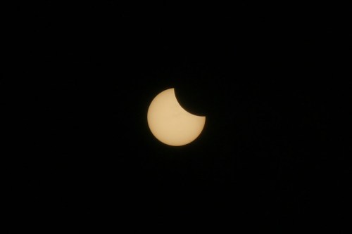 A partially eclipsed sun against a dark sky, showing a crescent shape.