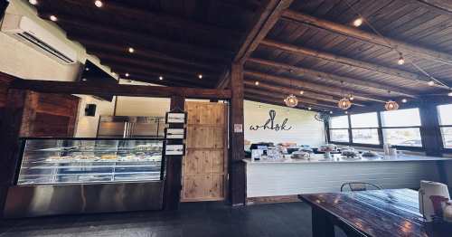 Cozy restaurant interior with wooden beams, a display case, and a welcoming atmosphere, featuring warm lighting.