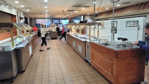 A spacious buffet restaurant with food stations and customers serving themselves. Brightly lit and inviting atmosphere.