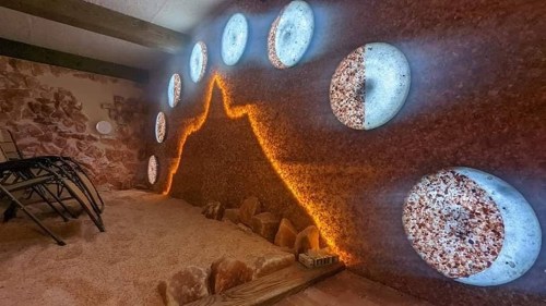 A serene salt room with glowing circular lights and a textured salt wall, creating a calming atmosphere.