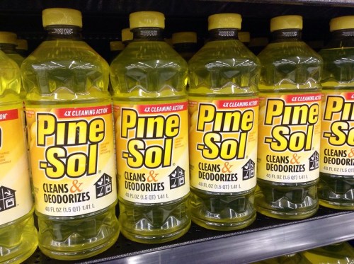 Bottles of Pine-Sol cleaner lined up on a store shelf, featuring bright yellow labels with cleaning and deodorizing claims.