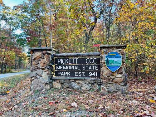 Sign for Pickett CCC Memorial State Park, established in 1941, surrounded by autumn foliage and trees.