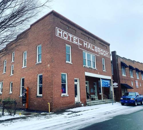 A brick building with "Hotel Halbrook" sign, snowy ground, and parked blue car nearby.