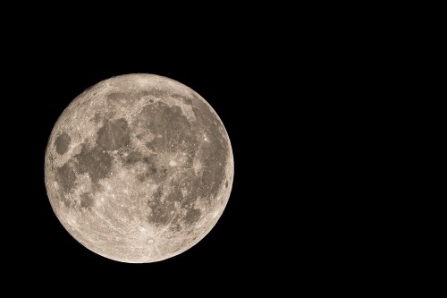 A close-up view of a full moon against a black sky, showcasing its craters and surface details.