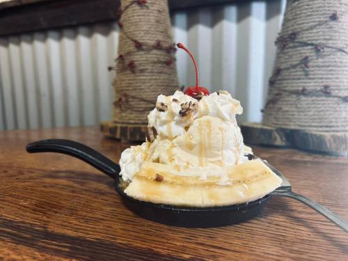 A banana split served in a small skillet, topped with ice cream, whipped cream, nuts, and a cherry.