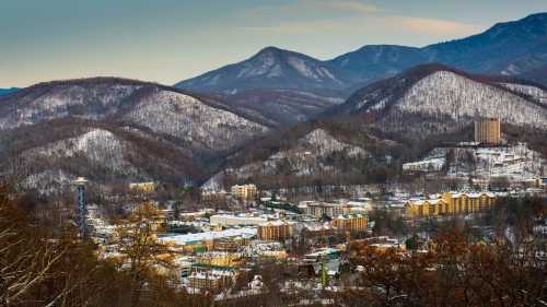 A scenic view of snow-covered mountains and a small town nestled in the valley, with a clear sky above.