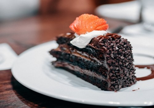 A slice of chocolate cake topped with a strawberry and whipped cream, served on a white plate.