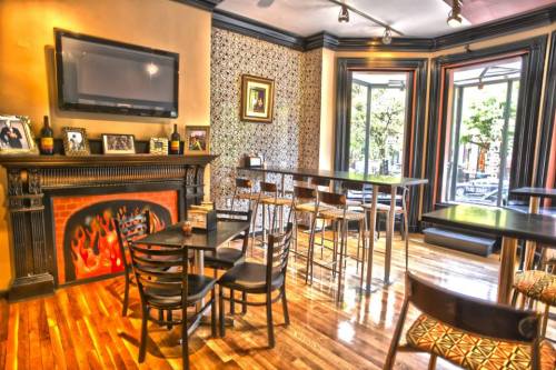 Cozy interior of a cafe with wooden floors, tall tables, and a decorative fireplace. Large windows let in natural light.
