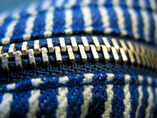 Close-up of a blue and white striped fabric with a metallic zipper, showcasing the teeth and stitching details.