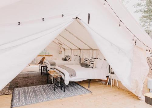 A cozy glamping tent with two beds, stylish decor, and warm lighting, set in a natural outdoor environment.