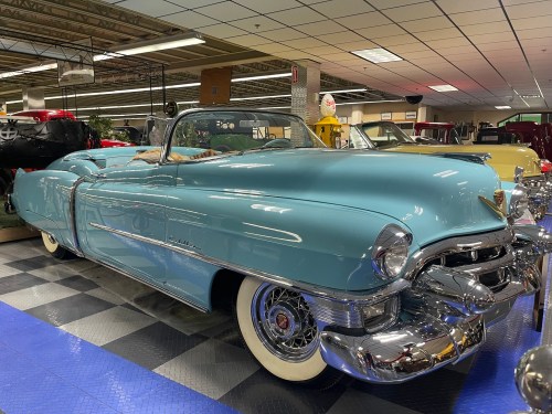 A vintage blue convertible car displayed in a museum, showcasing its classic design and shiny chrome details.