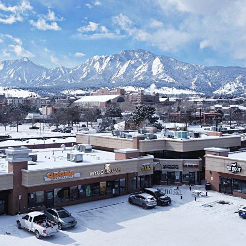 Snow-covered shopping plaza with mountains in the background and clear blue skies.
