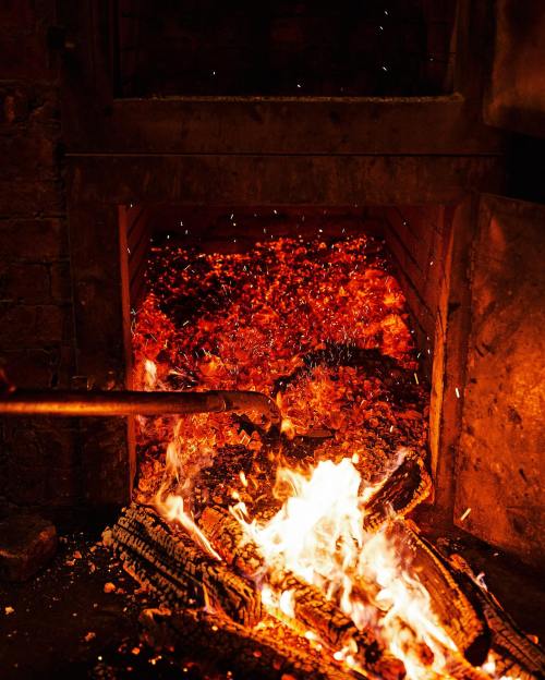 A glowing furnace filled with bright orange flames and glowing embers, creating a warm, intense atmosphere.