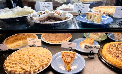 A display case filled with various pies, including chocolate cream, pecan, and banana cream, with labels for each.