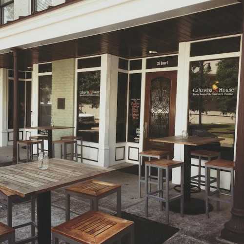 Exterior of Cahawe House restaurant with outdoor seating and wooden tables on a sunny day.