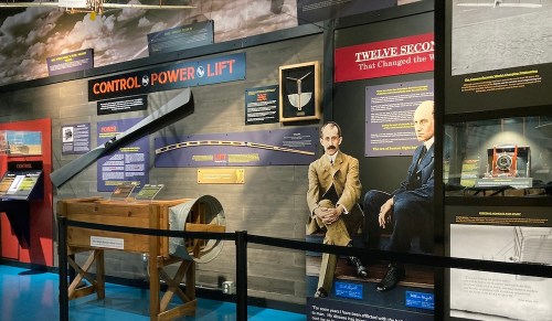 Exhibit showcasing aviation history with displays on control, power, and lift, featuring historical figures and artifacts.