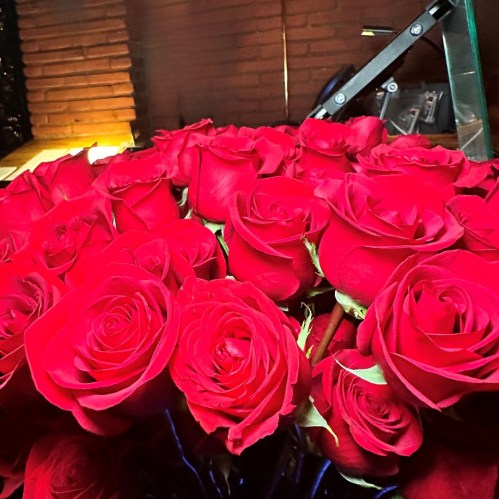 A close-up of vibrant red roses arranged closely together, showcasing their lush petals and rich color.