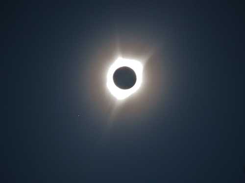 A solar eclipse with a dark moon silhouetted against a bright halo of sunlight.