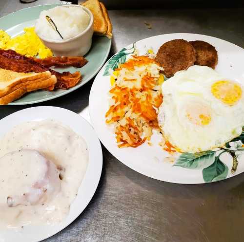 A hearty breakfast spread featuring eggs, bacon, toast, hash browns, biscuits with gravy, and a side of grits.