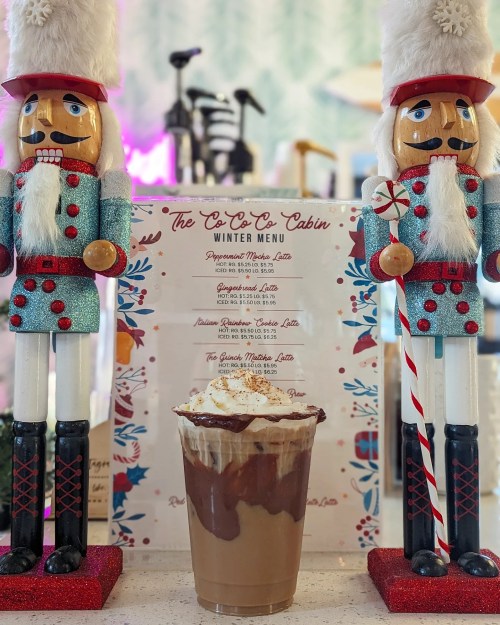 Two nutcracker figures flank a festive winter menu, with a frosty drink topped with whipped cream in the foreground.
