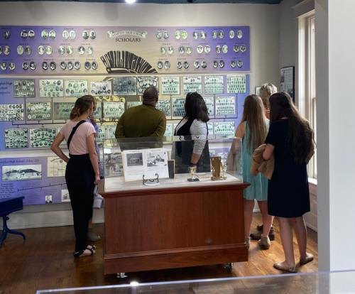 A group of visitors examines a display of historical photos and information in a museum setting.
