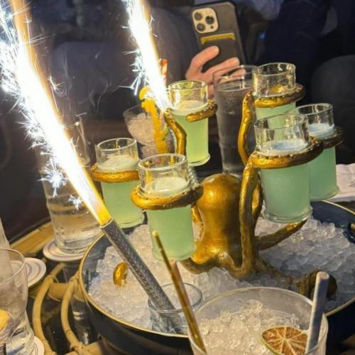 A decorative drink display with shots, ice, and sparklers, featuring an octopus-shaped holder.