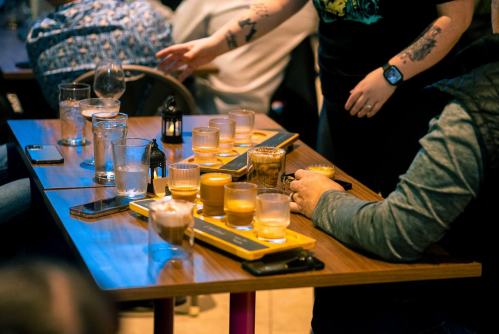 A table with various drinks, including cocktails and glasses, in a lively bar setting.
