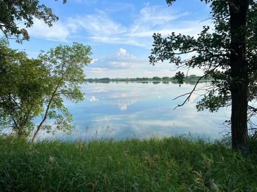 A serene lake reflects the sky, framed by lush greenery and trees on the shore.