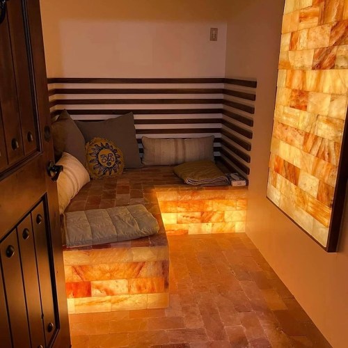 Cozy room with salt block walls, a cushioned seating area, and warm lighting, creating a relaxing atmosphere.