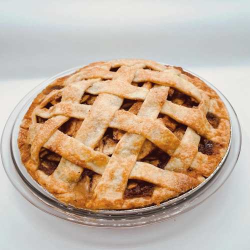 A freshly baked pie with a golden lattice crust, sitting in a clear glass pie dish.