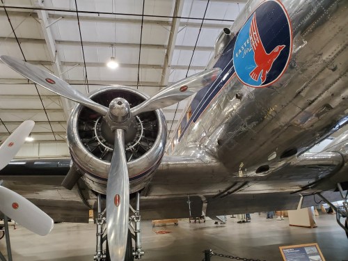 Close-up of a vintage airplane's propeller and fuselage, showcasing polished metal and a colorful logo.