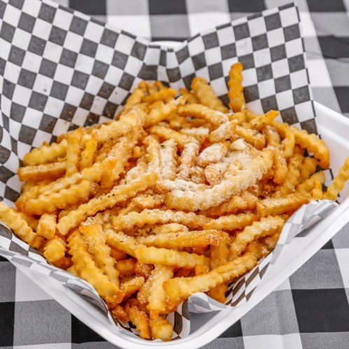 A serving of golden crinkle-cut fries topped with grated cheese, served in a checkered paper-lined tray.