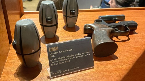 Display featuring props from the film "Looper," including a gun and futuristic grenades, with a descriptive plaque.