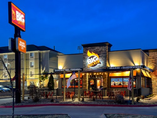 Exterior of Big Chicken restaurant at dusk, featuring a sign, outdoor seating, and a welcoming atmosphere.
