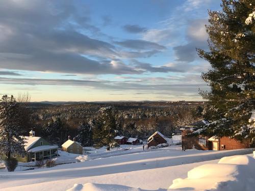 A snowy landscape with distant hills, scattered houses, and a clear sky, creating a serene winter scene.