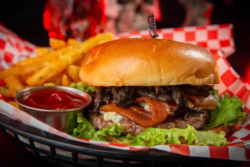 A juicy burger with bacon, mushrooms, and lettuce, served with fries and ketchup in a checkered basket.
