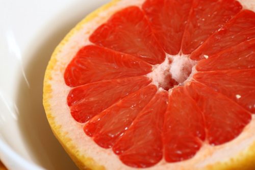 Close-up of a halved grapefruit, showcasing its vibrant red flesh and yellow rind.