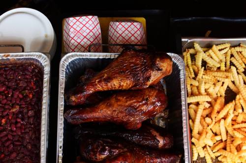A tray of grilled chicken legs, alongside sides of beans and crinkle-cut fries.