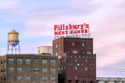 Historic Pillsbury's Best Flour building with a water tower in the background against a pastel sky.