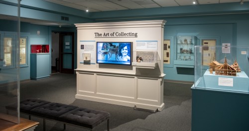 Exhibit titled "The Art of Collecting" featuring displays and a screen in a museum gallery.
