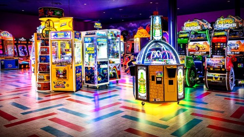 A vibrant arcade filled with colorful game machines and bright lights on a patterned floor.