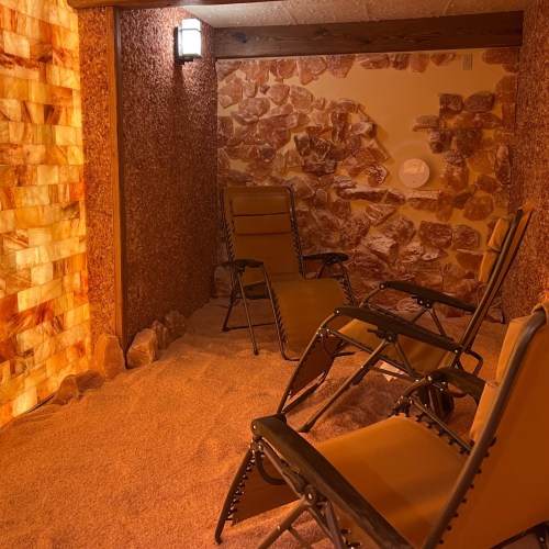 A cozy salt room with two reclining chairs and walls made of salt bricks, creating a relaxing atmosphere.