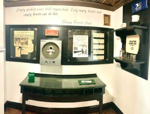 A display featuring historical items, a table, and a quote about empty pockets and heads on a wall.