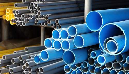 Stacks of blue PVC pipes arranged in a storage area, showcasing various diameters and lengths.