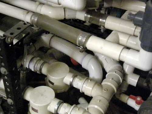 A complex arrangement of white PVC pipes and fittings in a mechanical space.