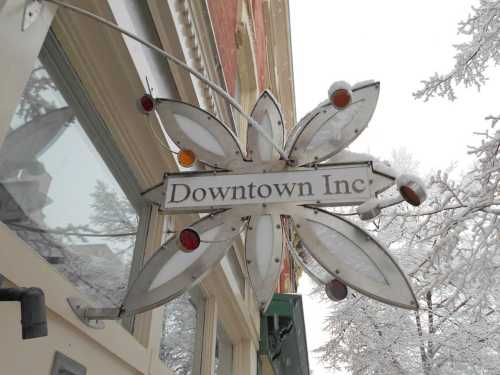 Sign for "Downtown Inc" with decorative leaf design, set against a snowy backdrop.