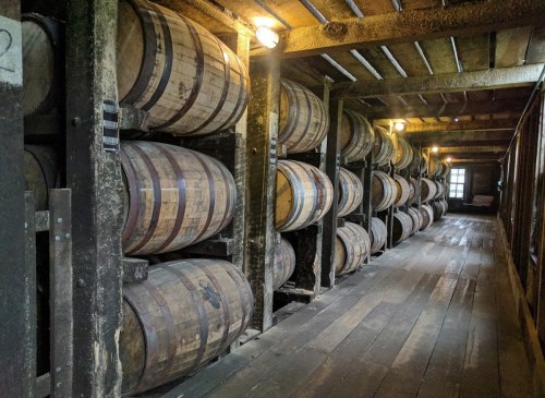 A dimly lit room with wooden barrels stacked against the walls, showcasing a rustic, historic atmosphere.