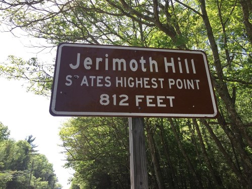 Sign for Jerimoth Hill, stating it is the state's highest point at 812 feet, surrounded by trees.